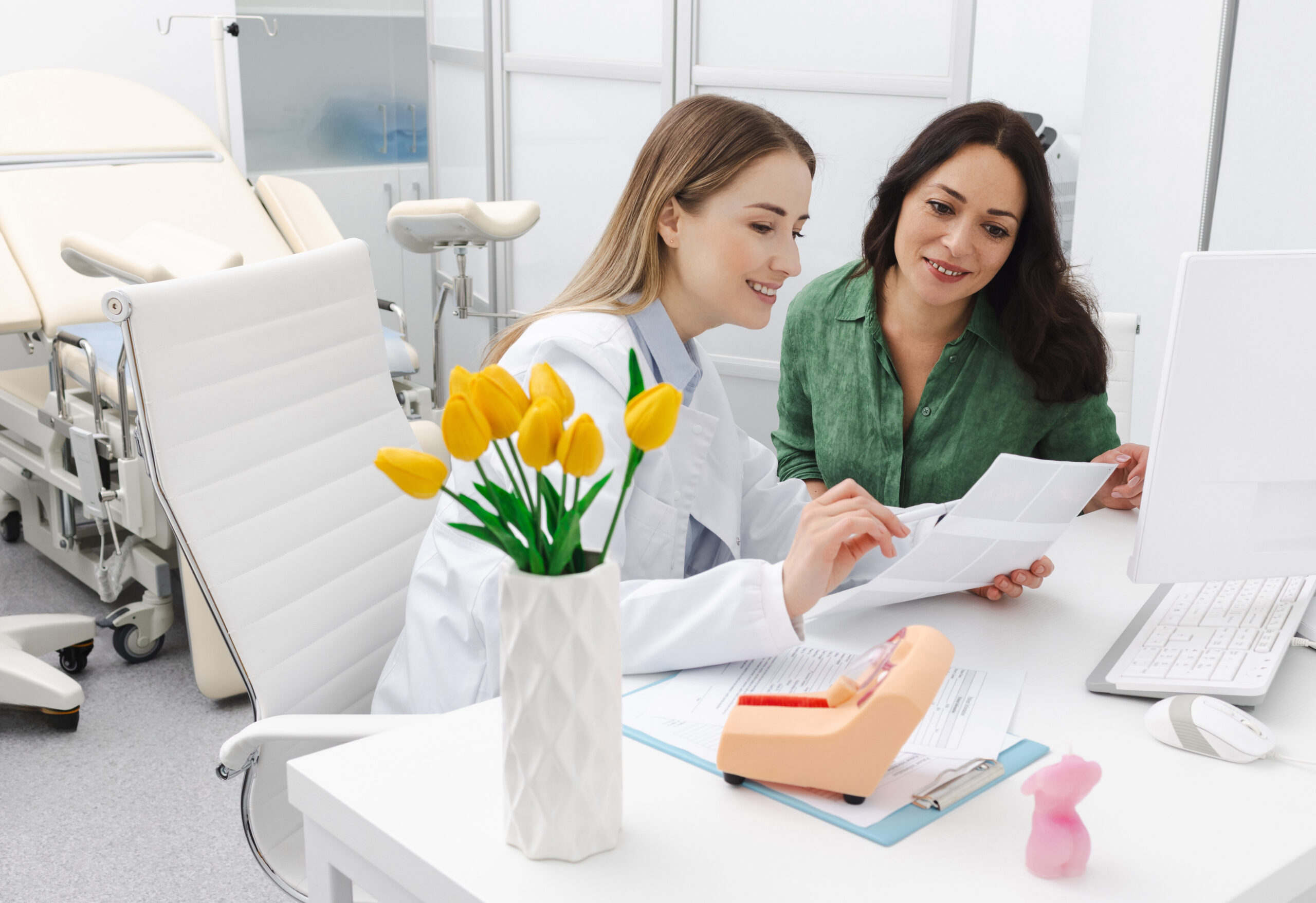 Gynecologist reviewing ultrasound of her pregnant patient while prenatal screening 1st trimester in gynecology clinic.